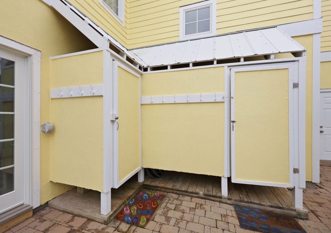 A covered outdoor shower enclosure provides a practical rinse-off spot with privacy screens, easy access from the patio, and thoughtful weather protection overhead.