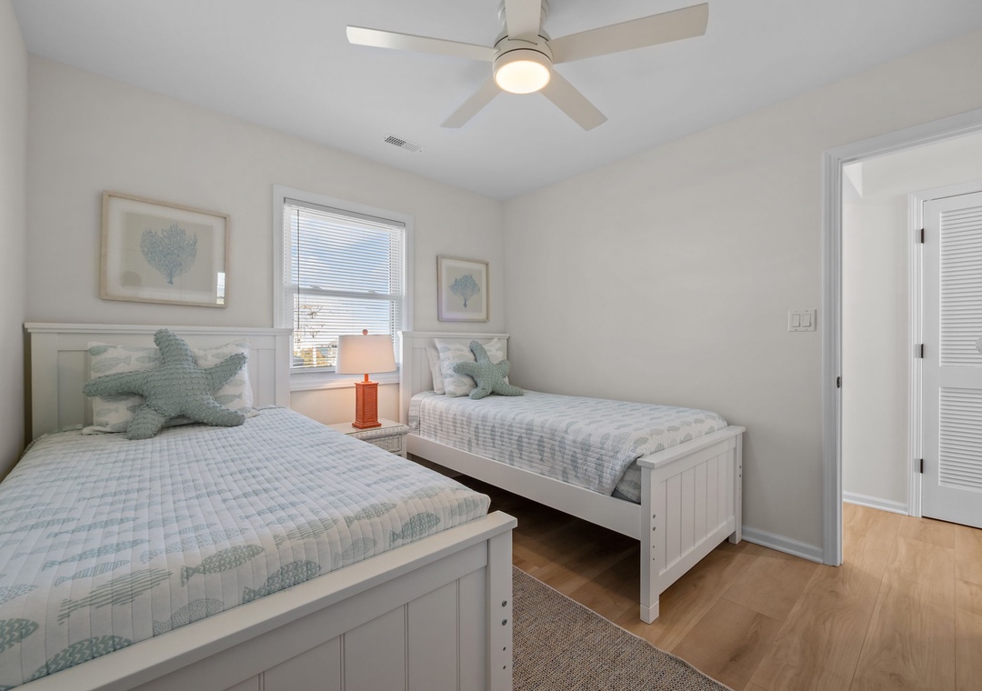 Twin beds dressed in soft coastal linens create your perfect retreat, with ocean-inspired decor and a gentle ceiling fan for comfort.