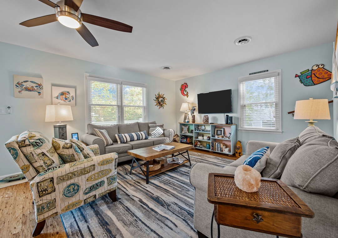 Unwind in your cheerful living room with plush seating, playful coastal decor, and natural light streaming through windows.