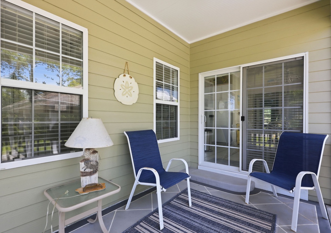 Covered porch with comfortable seating and nautical decor, offering a shaded spot to relax with your morning coffee or unwind after a day of beach adventures.