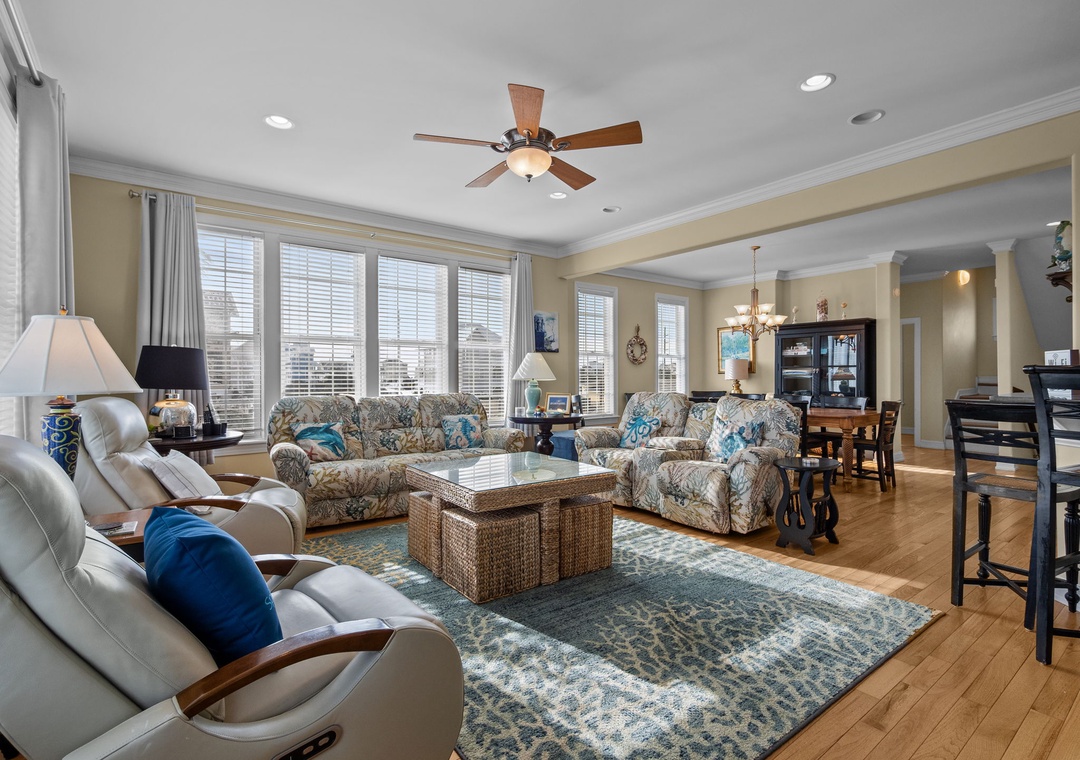 Relax in this spacious living room with comfortable seating, warm natural light streaming through large windows, and an open layout perfect for gathering.