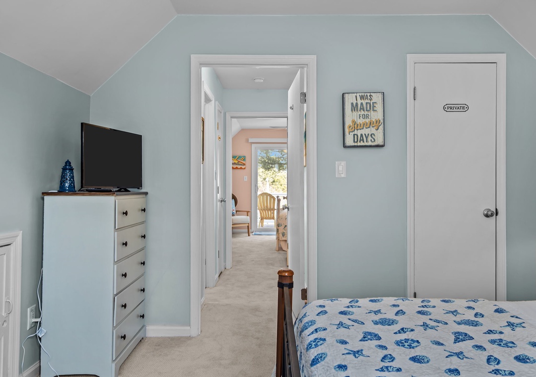 Your bright bedroom features a wall-mounted TV, spacious dresser, and charming coastal decor creating the perfect retreat for restful nights.