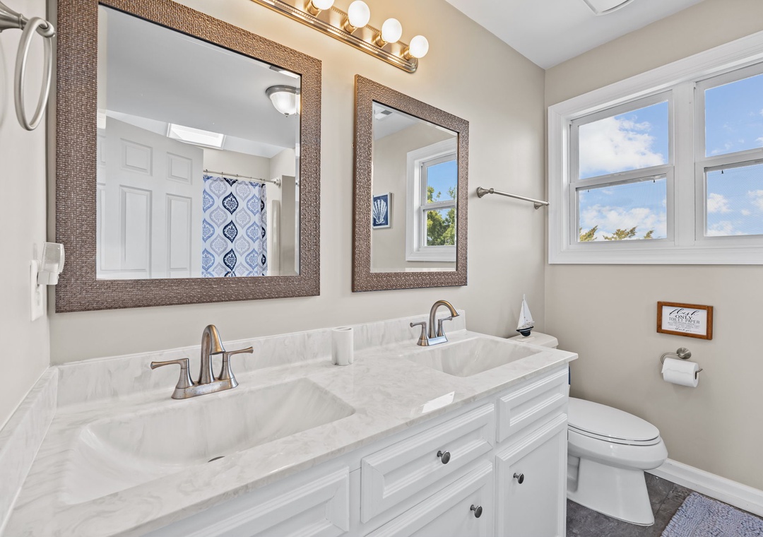 Refresh in this elegant dual-sink bathroom with marble countertops, stylish mirrors, and bright natural light streaming through the windows.