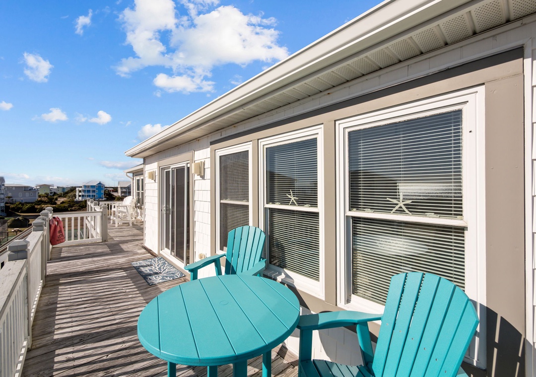 Relax on your private deck with turquoise coastal-style chairs and table, soaking in the neighborhood views.