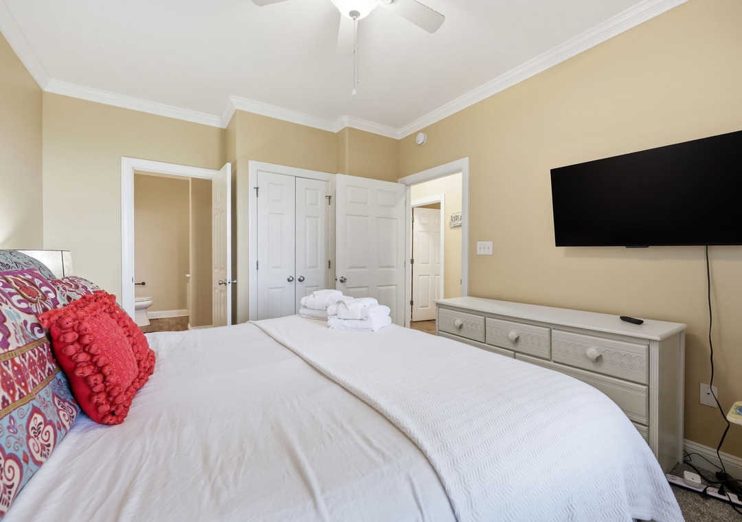 Unwind in your serene bedroom, where plush linens, a ceiling fan, and wall-mounted TV create your perfect retreat. Fresh towels and ensuite access ensure comfort and convenience throughout your stay.