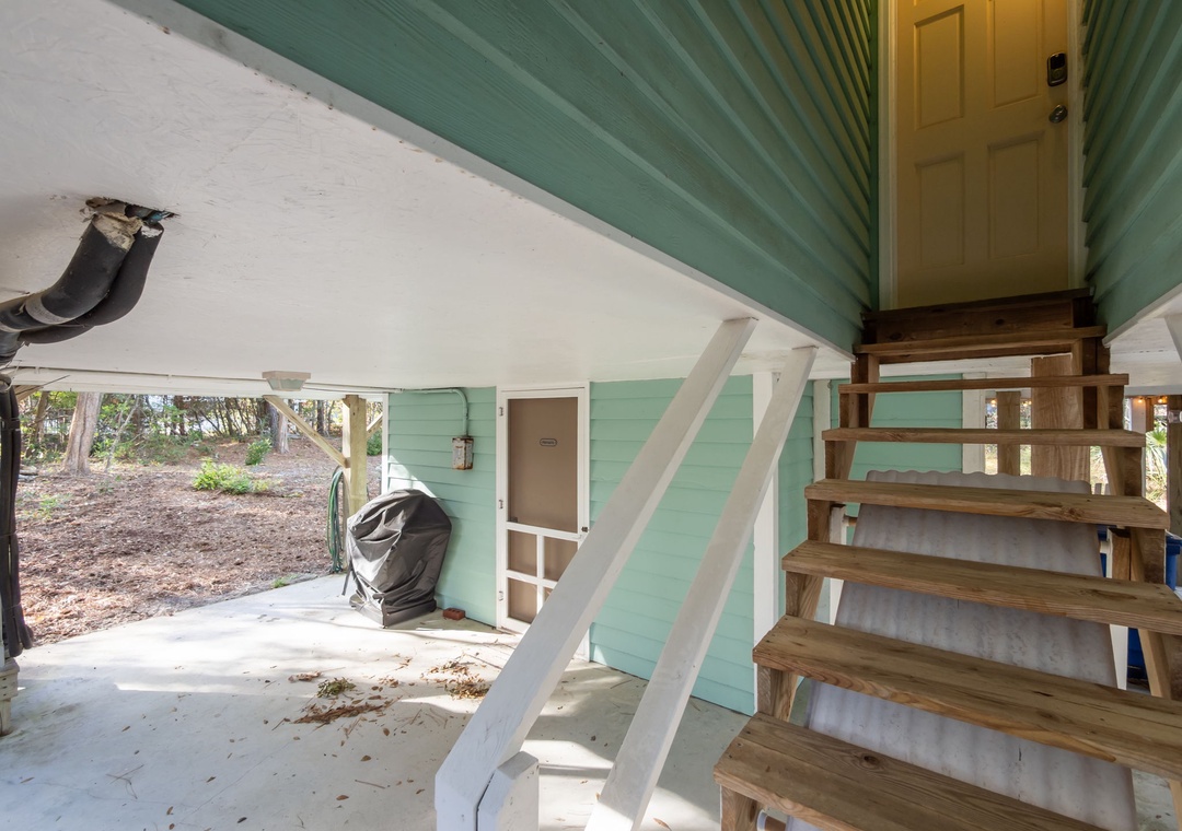 Ground-level covered area with storage and outdoor stairs leading to your beachside retreat.
