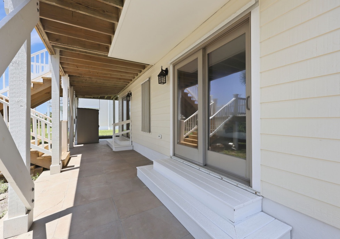 A covered walkway leads to sliding glass doors, offering a quiet outdoor area for relaxing and enjoying the surroundings.