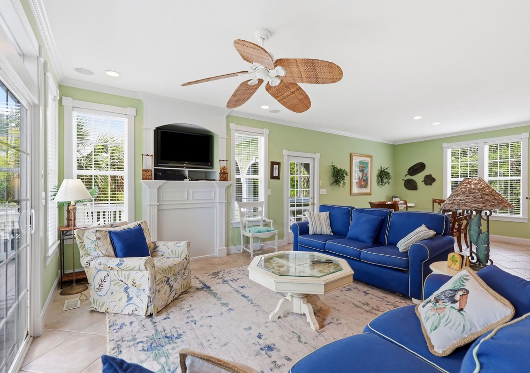 Sink into plush coastal comfort and unwind in this sun-drenched living space, where calming hues and breezy ceiling fans create your perfect island retreat.