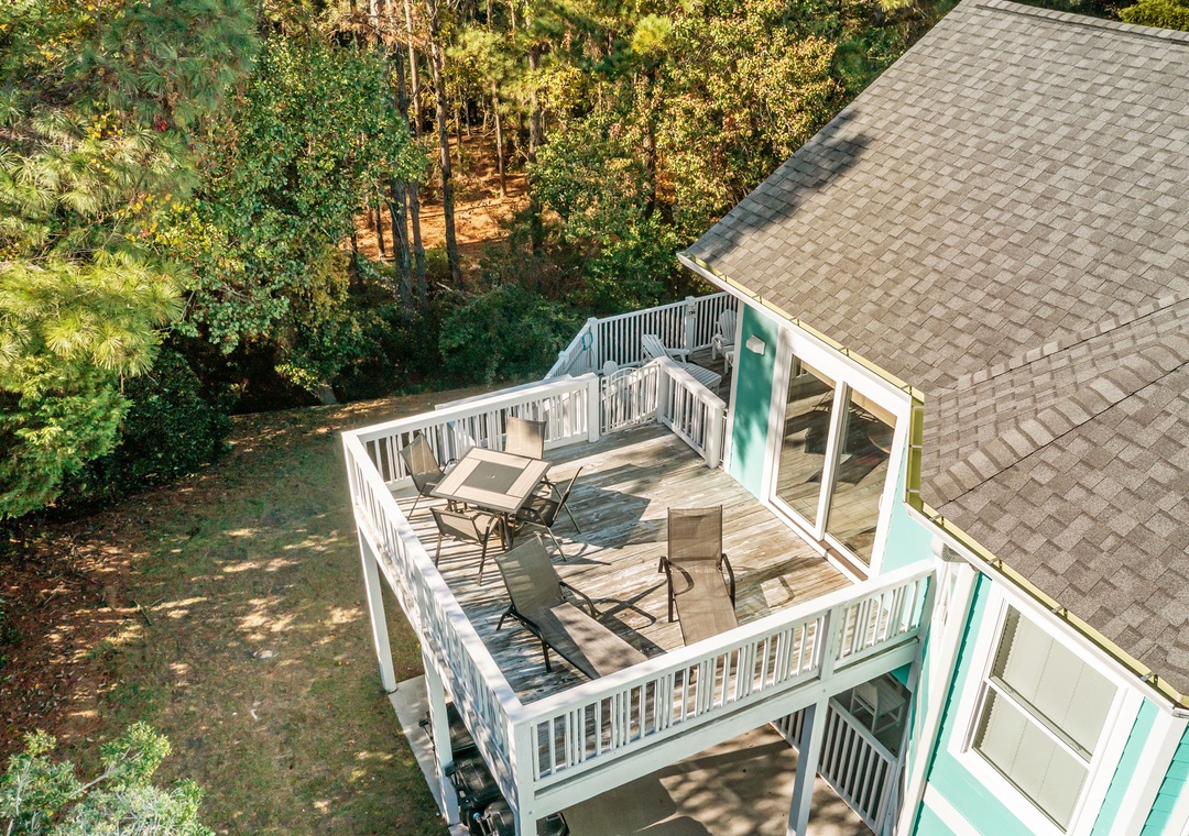 Aerial view of the property's elevated deck featuring outdoor seating surrounded by lush forest canopy.