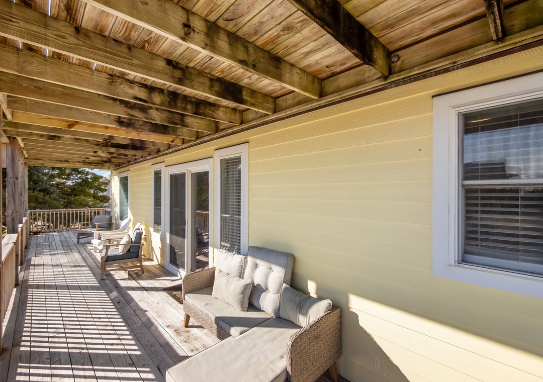 Your private covered balcony invites relaxation with comfortable seating and scenic views beyond the treetops.