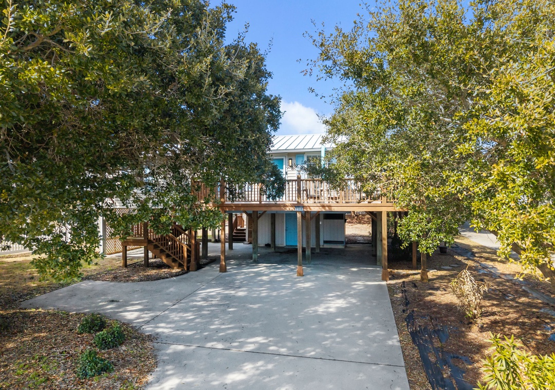 Charming elevated home nestled among mature trees with covered parking and outdoor deck areas.
