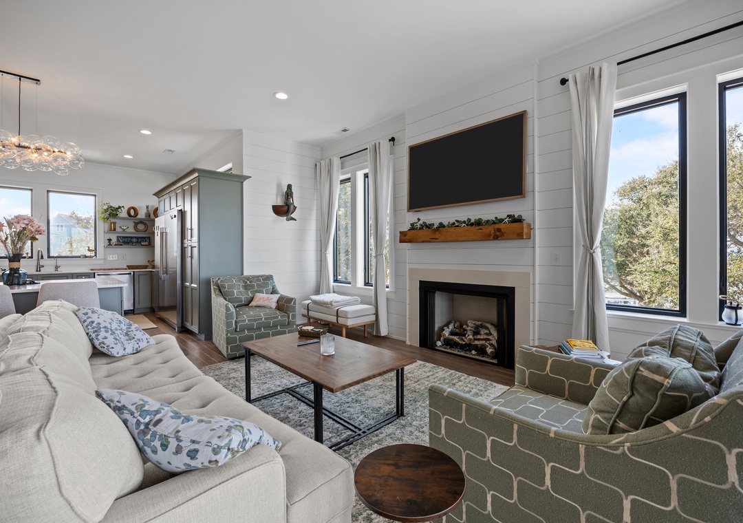 Gather by the fireplace in this bright living room, where modern comfort meets rustic charm with shiplap walls and treetop views.