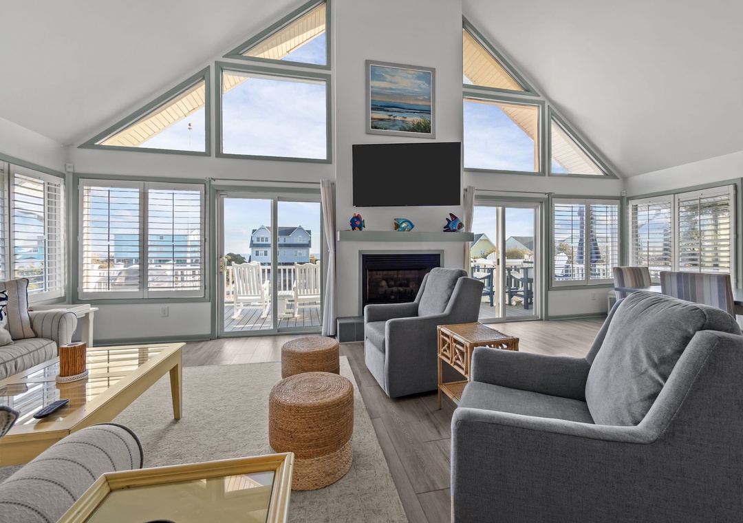 Relax in your bright living room with soaring ceilings, cozy fireplace, and stunning ocean views through floor-to-ceiling windows.