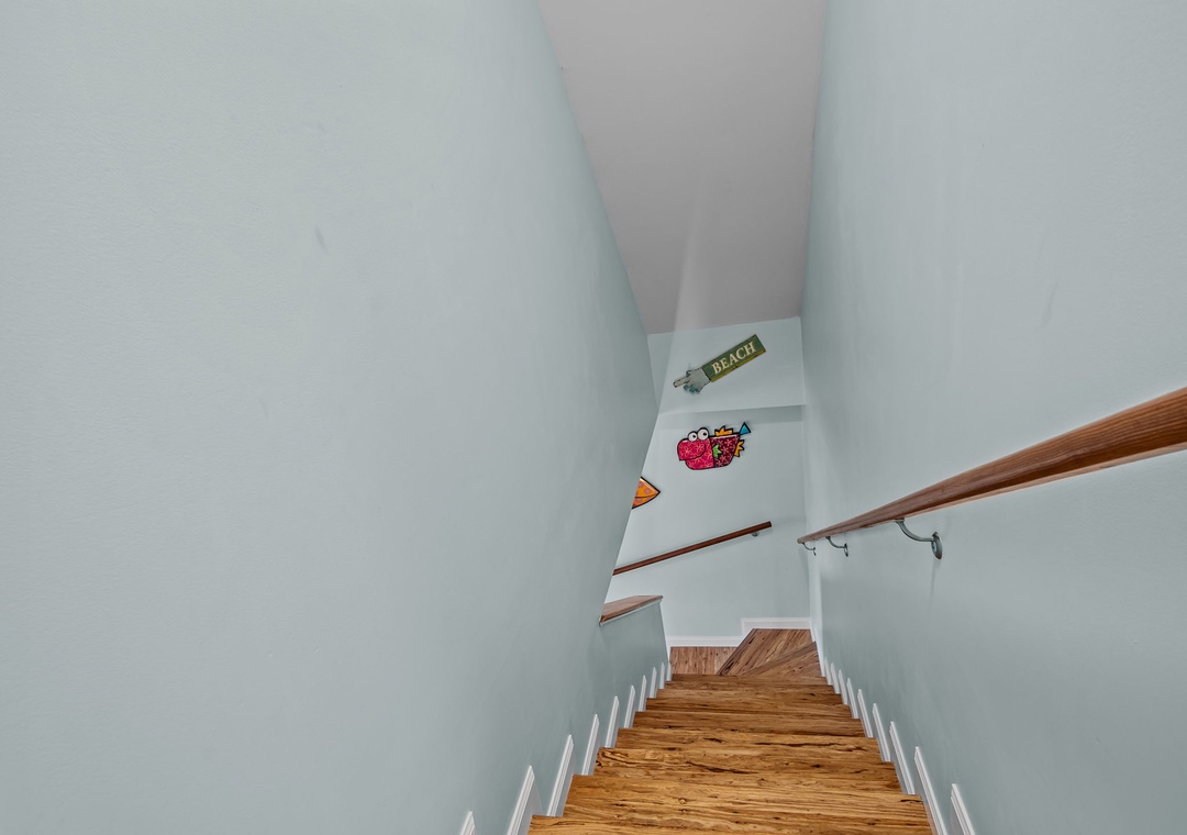 Climb these welcoming wooden stairs to discover your upstairs retreat, where charming vintage posters add personality to the bright walls.