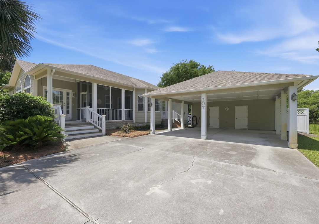 A charming single-story vacation home with covered carport, surrounded by mature landscaping and tropical palms in a quiet neighborhood—your coastal getaway awaits.