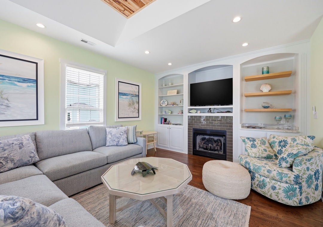 Settle into this bright, coastal living room where soft seating, a cozy fireplace, and beach-inspired decor invite you to unwind after a day of exploring.
