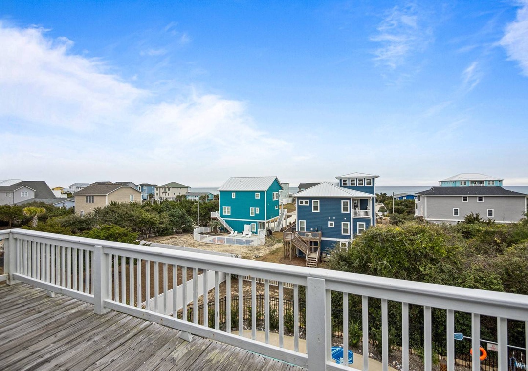 Peaceful coastal neighborhood with colorful beach houses stretching toward the horizon under endless blue skies.