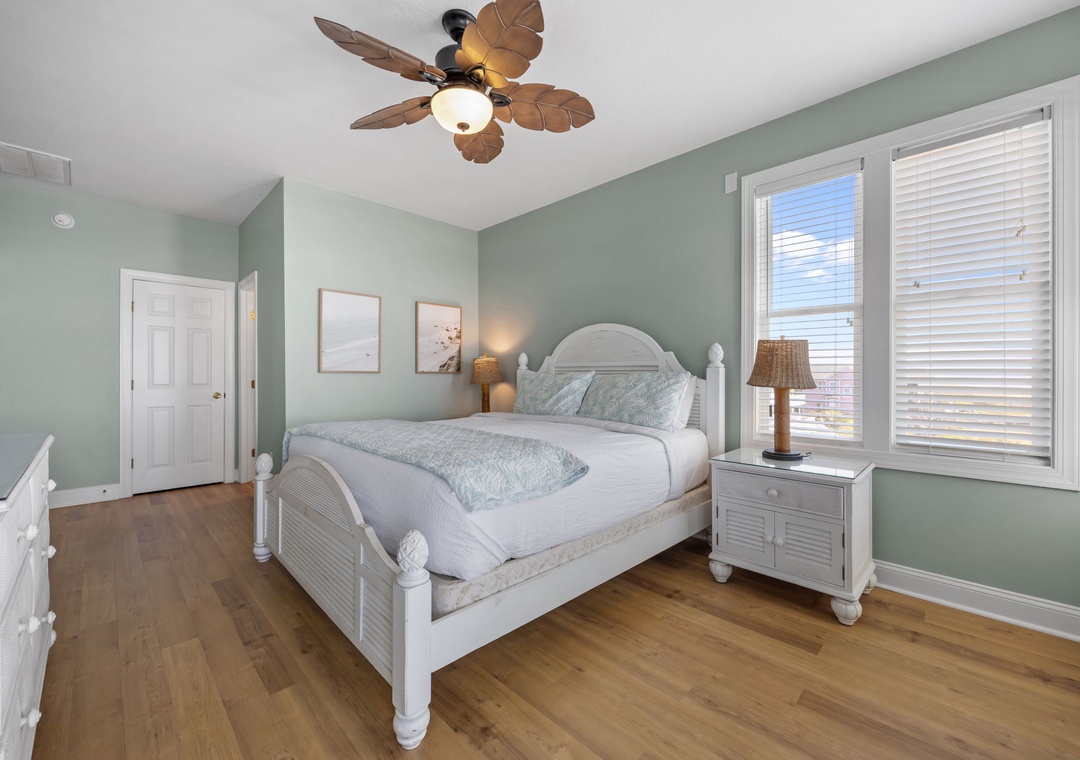 Your peaceful bedroom features crisp white coastal furniture, soothing seafoam walls, and tropical ceiling fan creating the perfect retreat for restful nights.