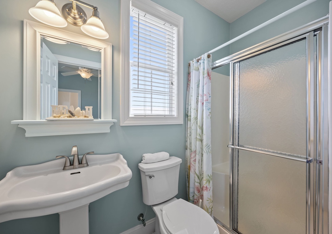 Refresh in your serene bathroom with soft aqua walls, classic fixtures, and natural light filtering through the window.