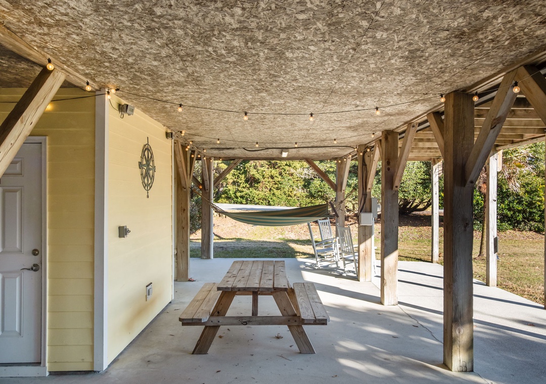 Your private covered patio beckons with a picnic table, hammock, and twinkling string lights—perfect for morning coffee or evening relaxation in your outdoor sanctuary.