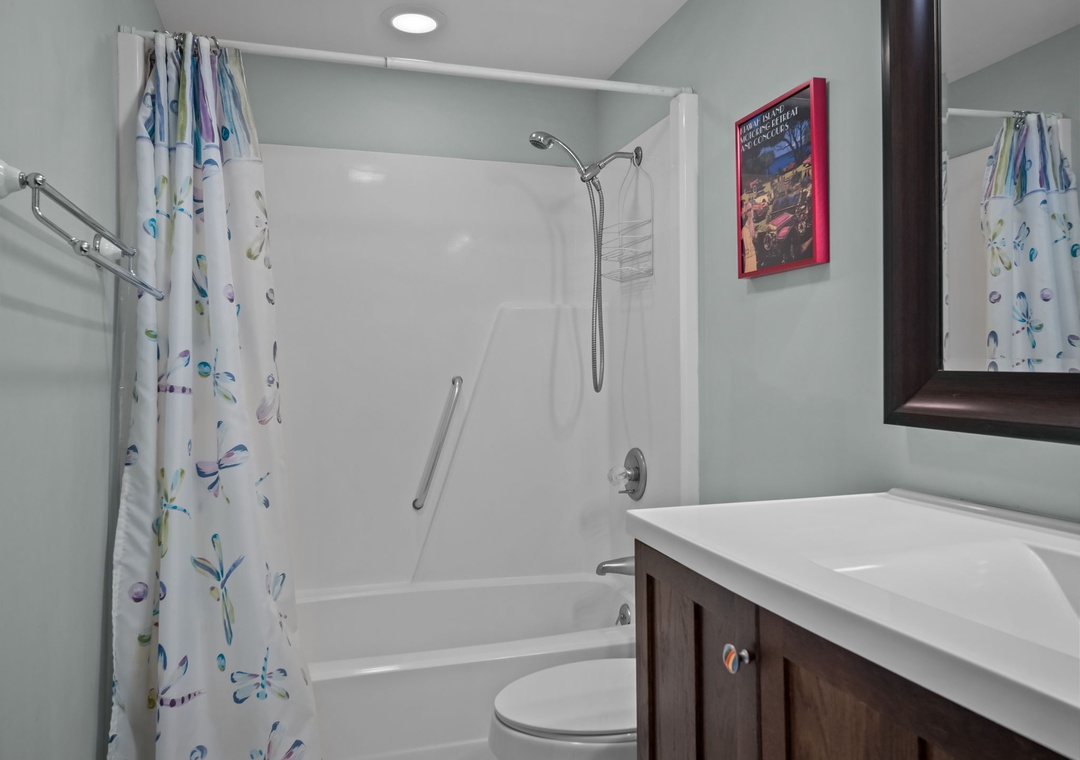 Step into your bright, accessible bathroom featuring a comfortable tub-shower combo with safety rails and cheerful floral curtains.