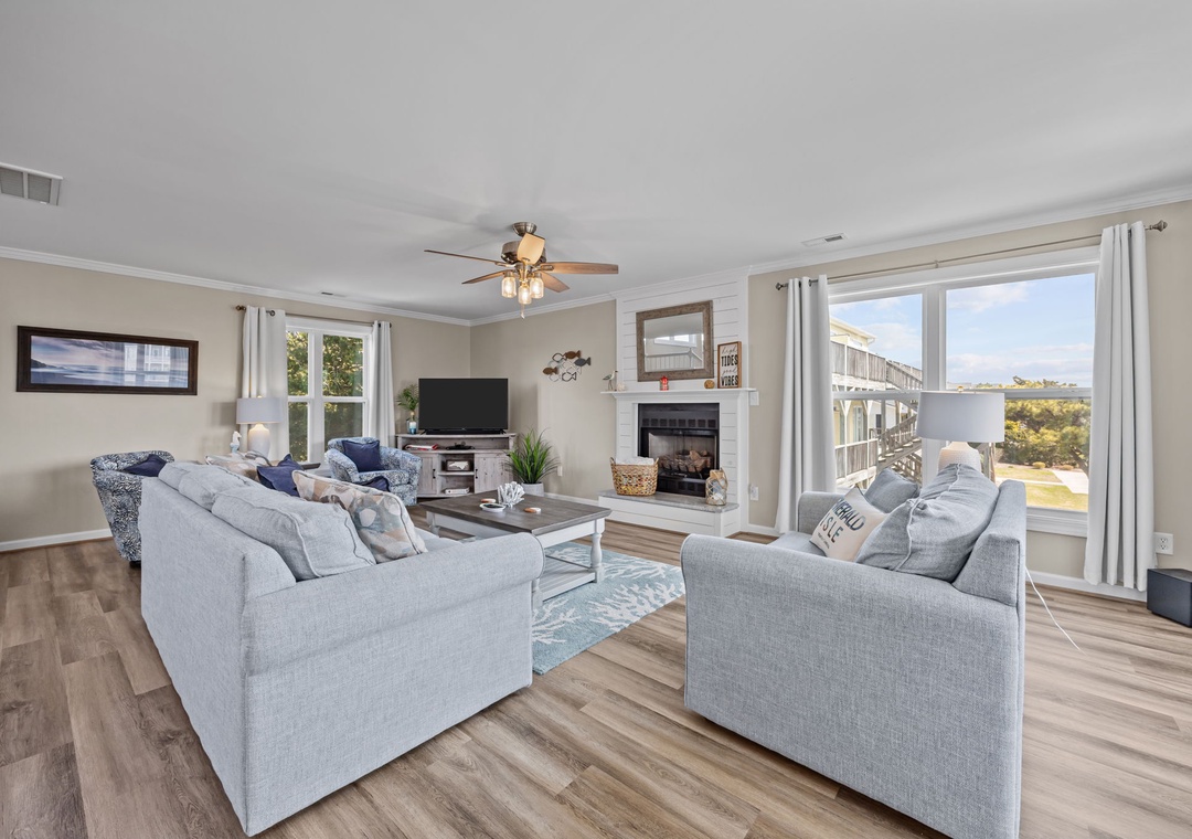 Unwind in your spacious living room featuring plush seating, warm fireplace, and panoramic windows showcasing stunning coastal views.