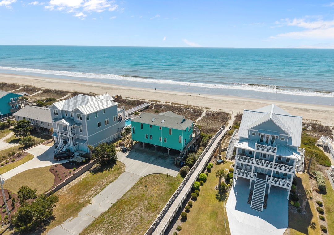 Colorful beachfront rental homes positioned steps from pristine sandy shores and turquoise waters.