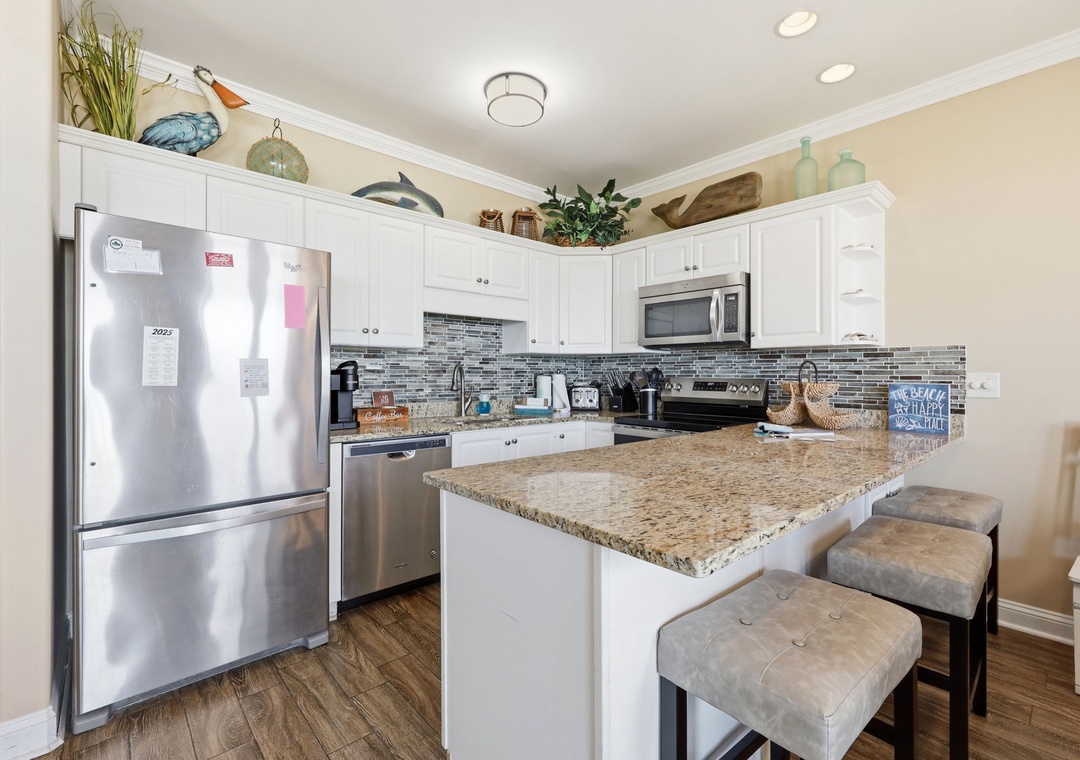 Your fully equipped kitchen invites you to cook and gather, with granite countertops, modern appliances, and stylish tile backsplash creating the perfect space to make vacation meals together.