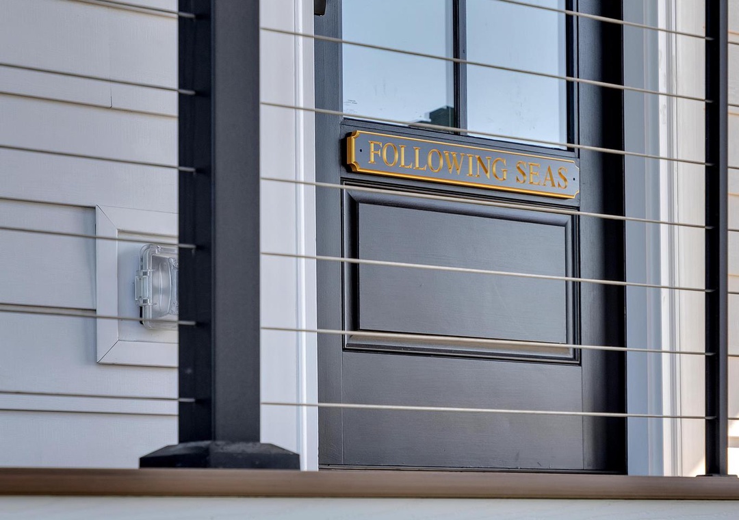 The entrance features a modern design with black-framed glass doors and elegant brass signage marking your arrival at Following Seas.