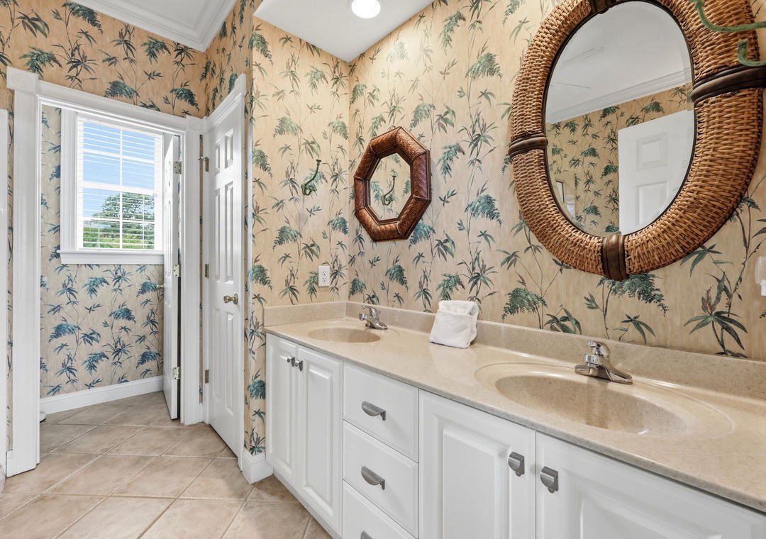 Refresh in your elegant dual-sink bathroom with charming tropical wallpaper, abundant natural light, and thoughtful coastal touches that bring relaxed island vibes to your daily routine.