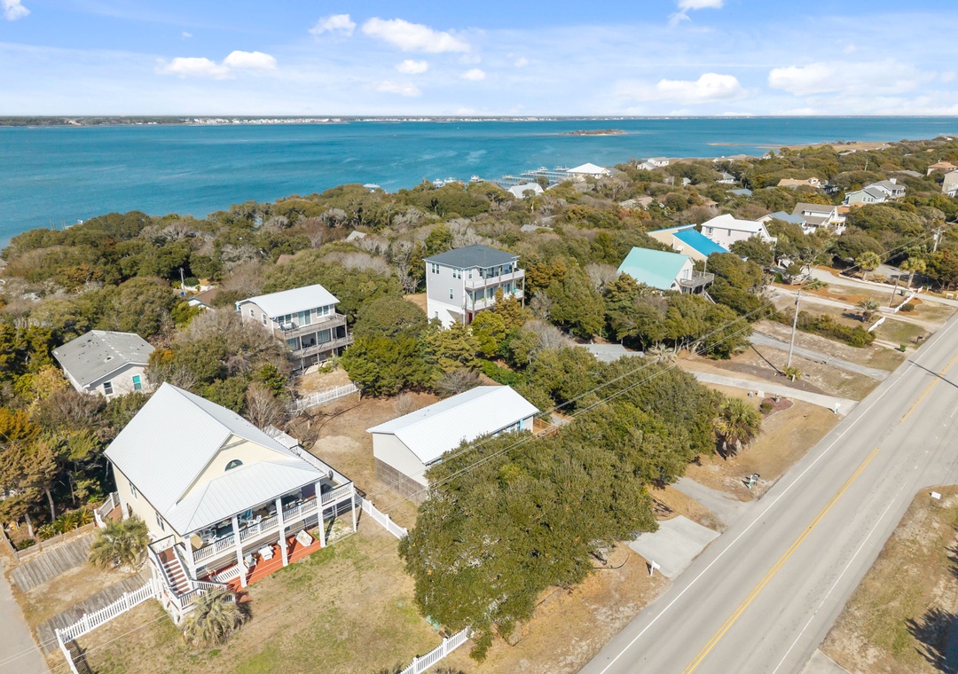 Coastal neighborhood with vacation homes nestled among trees, just steps from pristine turquoise waters and sandy shores.
