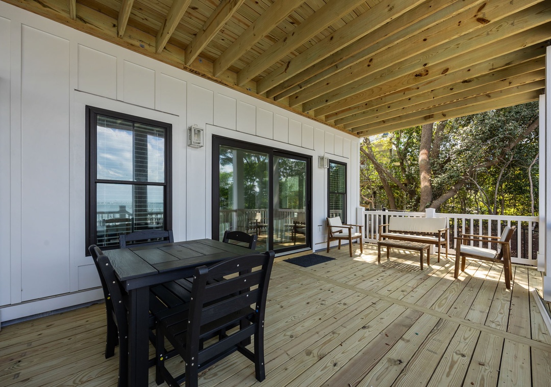 Your private covered deck offers peaceful dining under exposed beams, with comfortable seating overlooking mature trees.