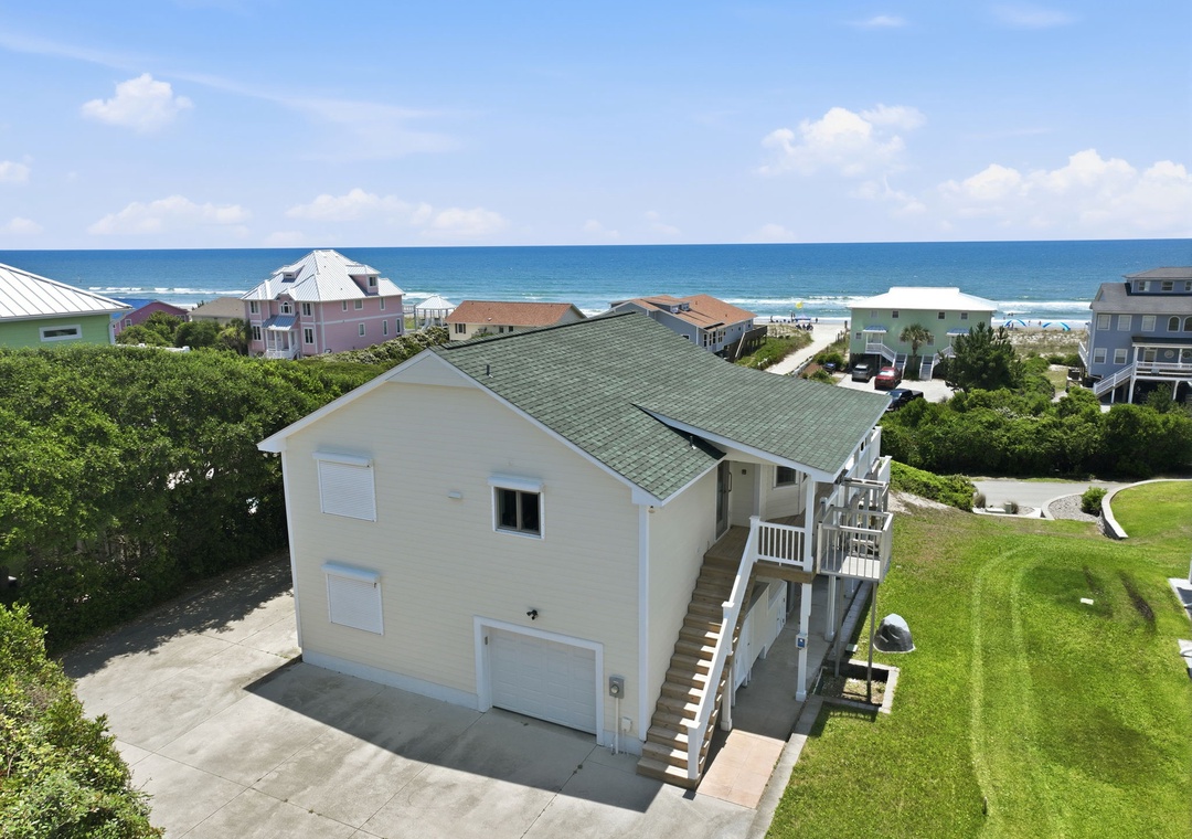 Coastal beach home nestled in a quiet residential neighborhood, just a short stroll from the ocean. Multiple levels of outdoor decking and proximity to sandy shores.