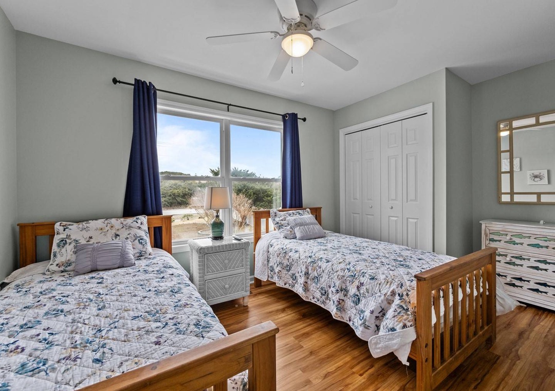 Your peaceful twin bedroom features comfortable beds with coordinated linens, natural light from large windows, and views of the surrounding landscape.