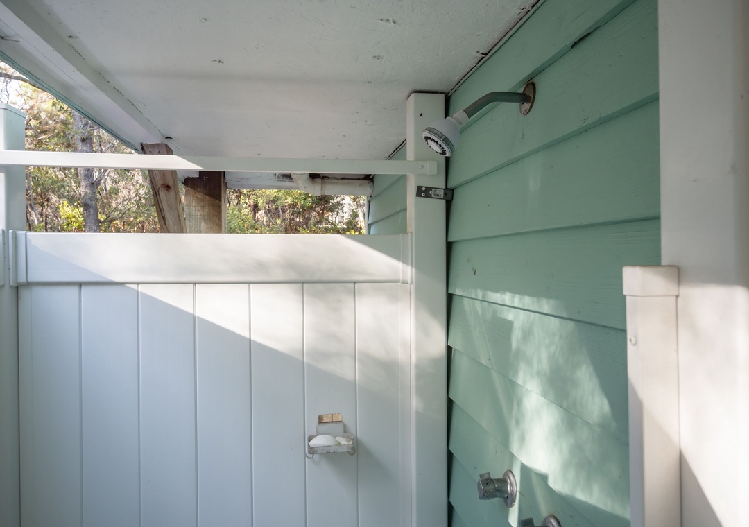 Rinse off under your private outdoor shower, where natural light filters through leafy trees for a refreshing open-air experience.