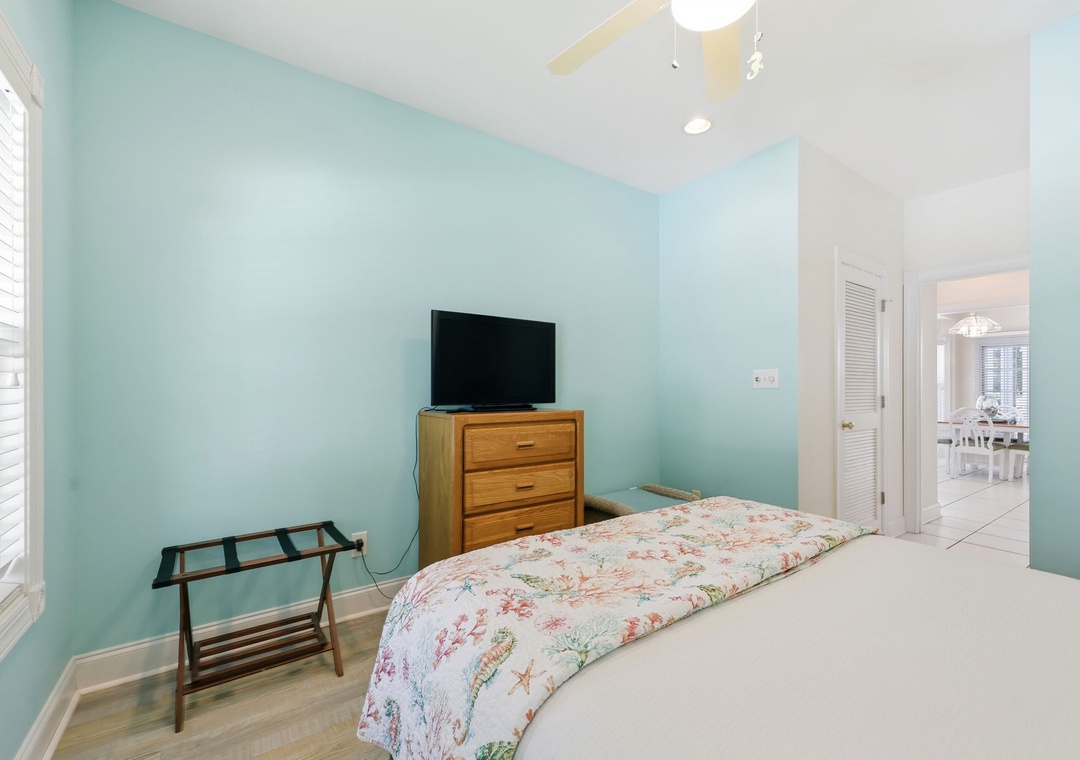 Relax in this serene bedroom with soft blue walls, a cozy bed, and your own flat-screen TV. Enjoy hardwood floors and bright natural light from the window.