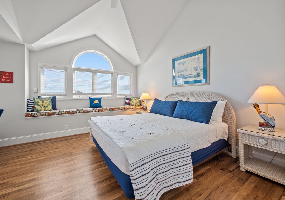 Wake up to natural light streaming through your arched window in this charming coastal bedroom, complete with a cozy reading nook.