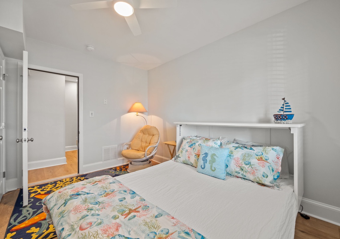 Drift off in your coastal-themed bedroom with whimsical ocean bedding and a cozy reading chair perfect for evening relaxation.