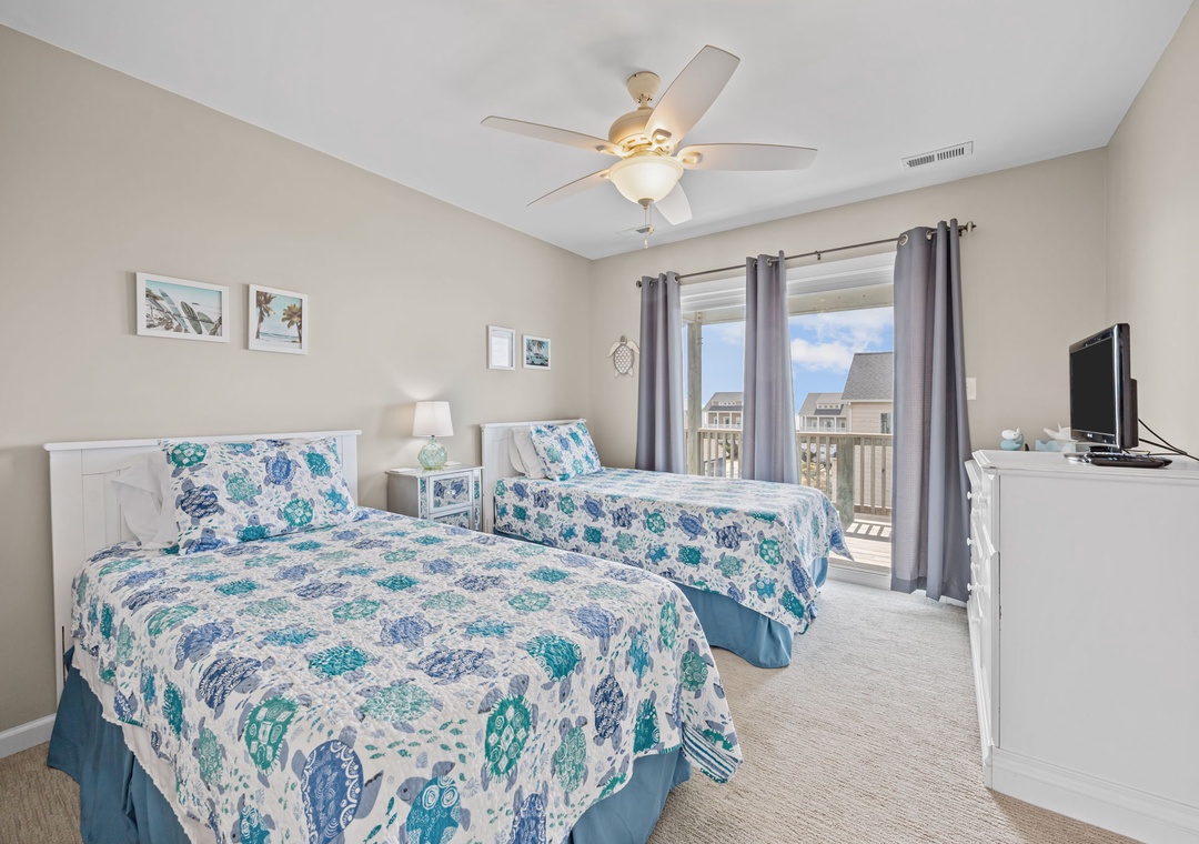 Two comfortable beds await you in this bright bedroom with calming coastal decor and your own balcony access.