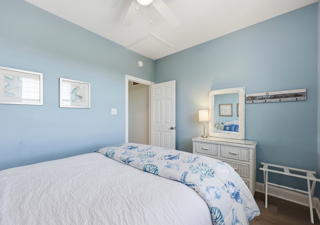 Picture yourself unwinding in this serene coastal bedroom, where soft blue walls and beach-inspired decor invite peaceful slumber after a day of adventure.