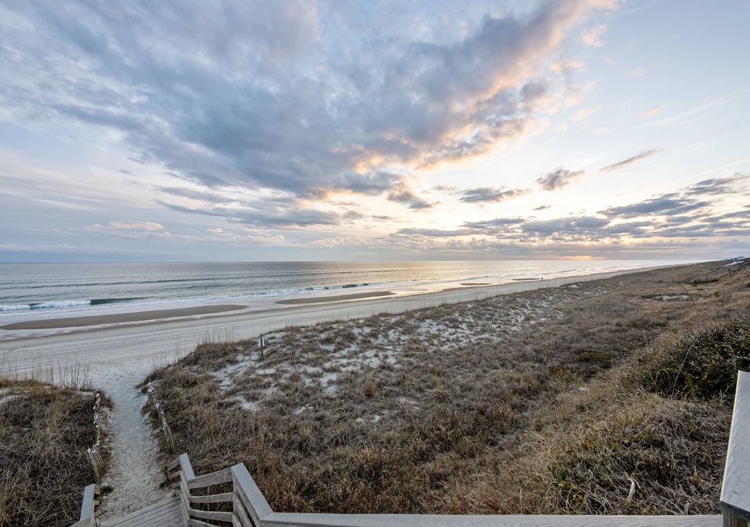 Stunning beachfront location with dramatic evening sky painting the horizon in soft pastels over pristine sandy shores.