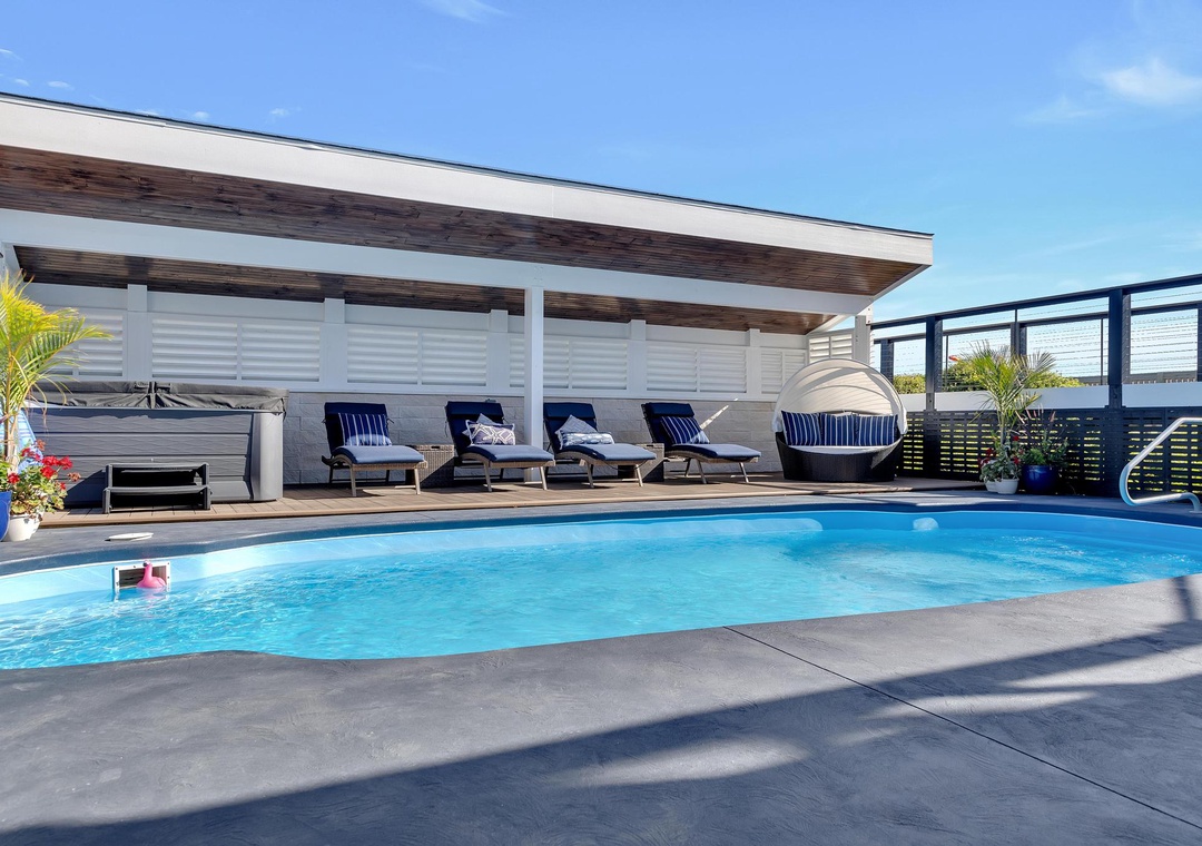 Picture yourself lounging by this sparkling pool, soaking up the sun on plush deck chairs. The modern pergola provides cool shade while tropical plants frame your private oasis—your perfect escape awaits.