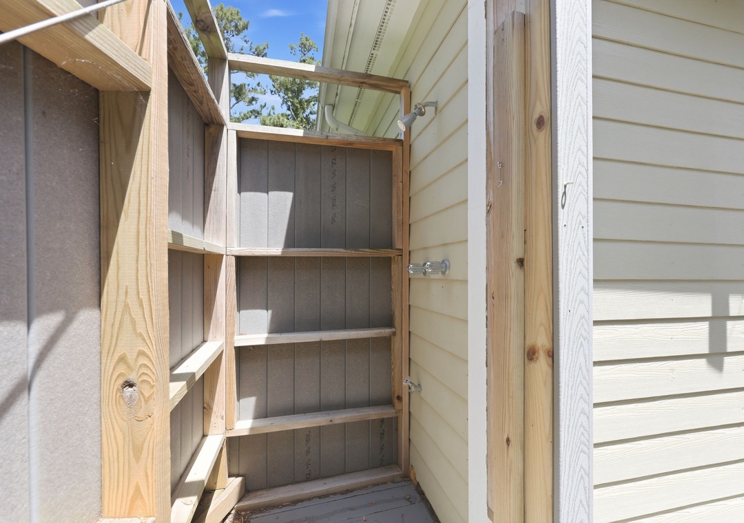 This outdoor storage cabinet provides convenient space for your belongings, nestled beside the property with open-air accessibility and natural light from the skylight above.