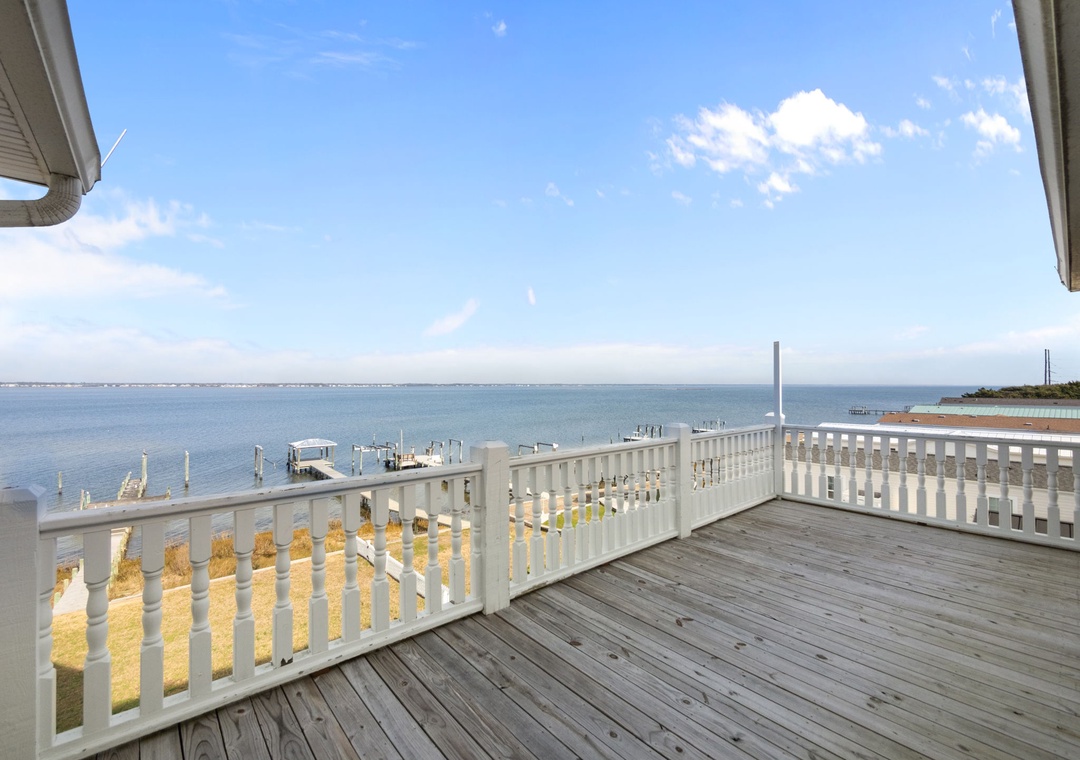 Your private deck overlooks peaceful waters and marina, where mornings begin with gentle waves and endless blue skies stretching to the horizon.
