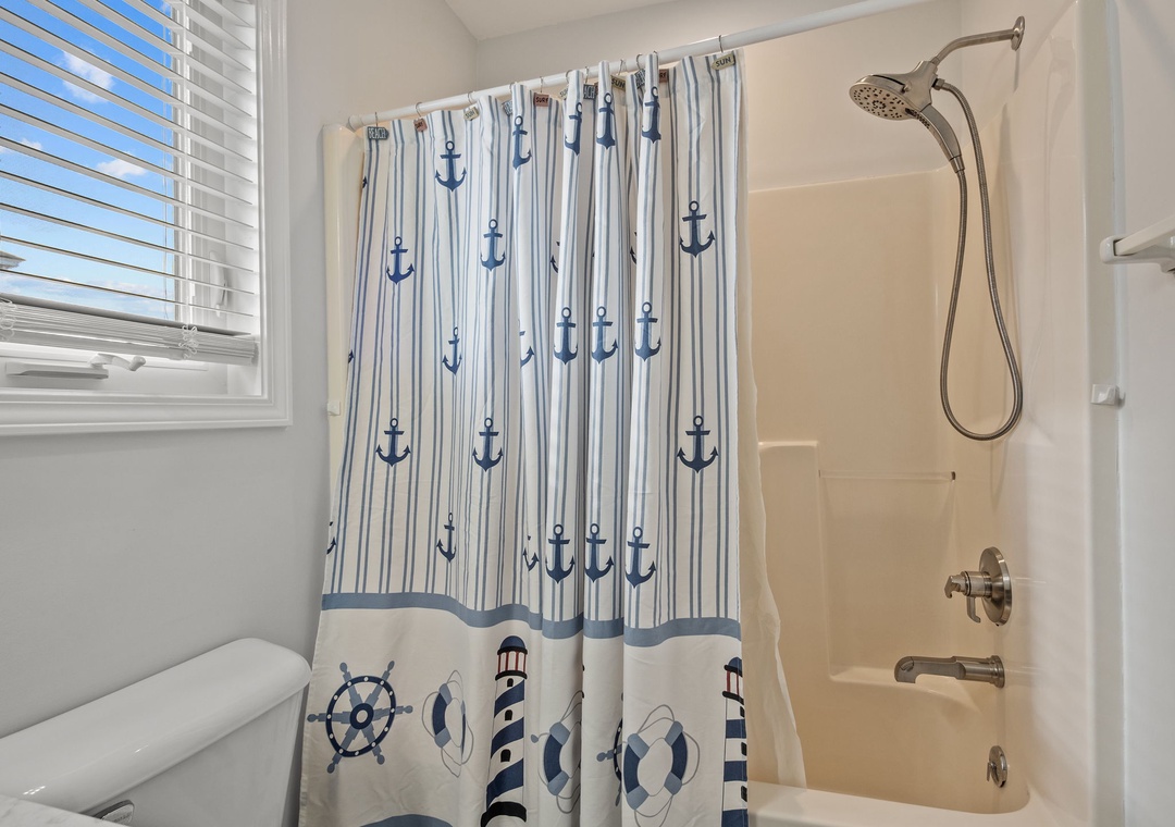 Step into your nautical-themed bathroom where a charming anchor-patterned shower curtain sets the coastal mood for refreshing morning routines.