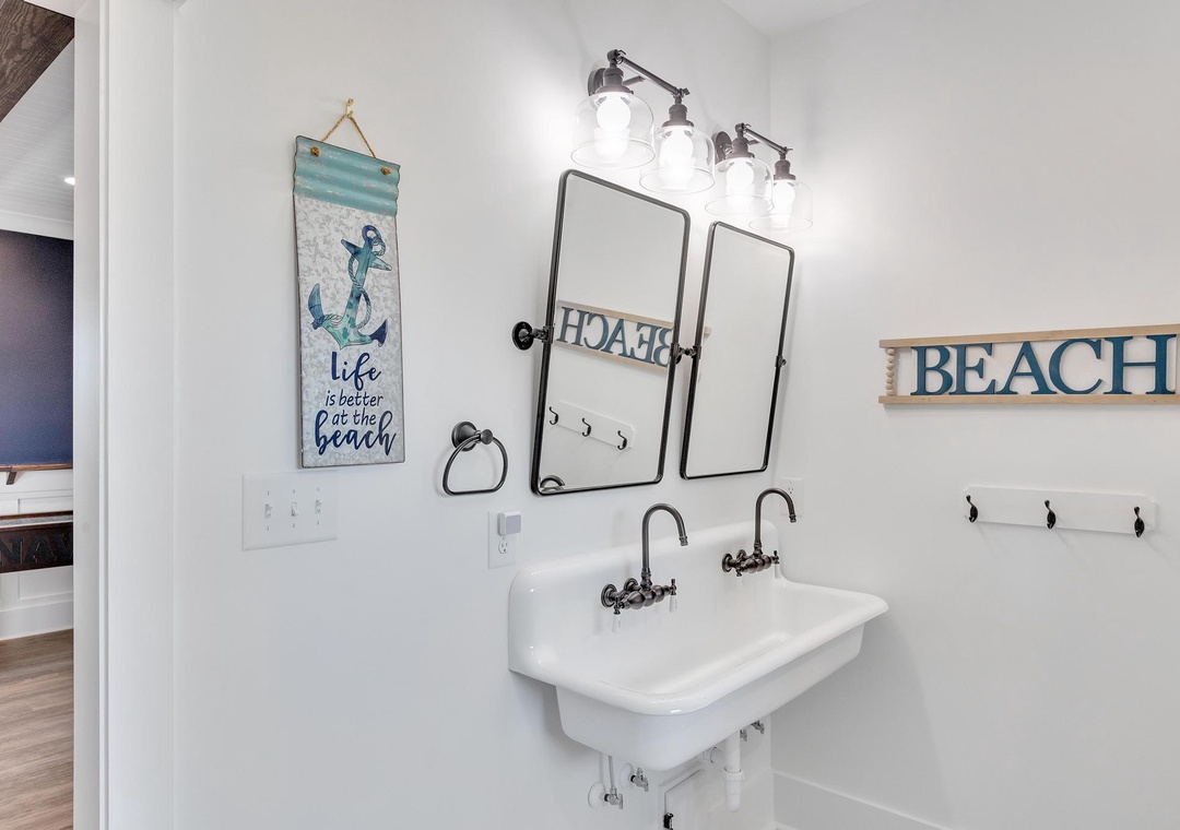 Freshen up in your charming coastal bathroom, where beach-inspired décor and a double trough sink create a relaxed, breezy vibe perfect for your seaside getaway.
