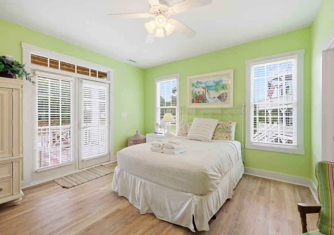 Step into your cheerful coastal retreat with bright green walls, fresh white linens, and a balcony door opening to sunny outdoor relaxation. You'll rest easy in this inviting, naturally lit space.