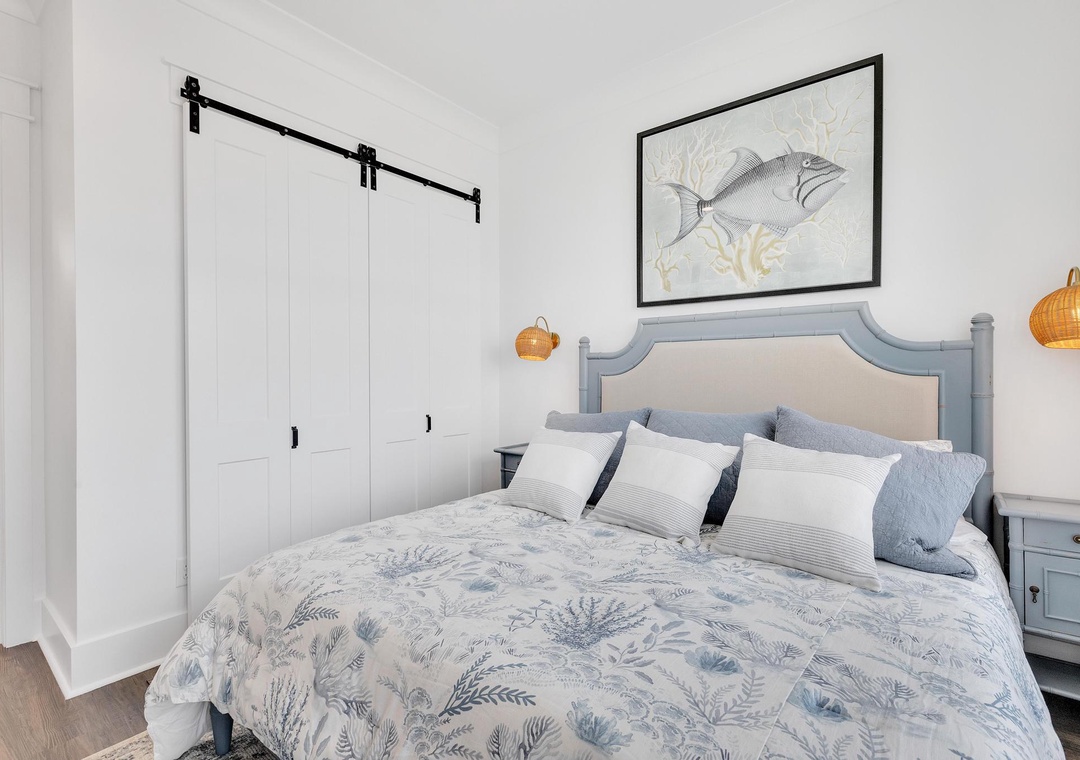 Drift off in this coastal-inspired bedroom featuring a barn door accent and ocean-themed decor that brings beachside tranquility to your stay.