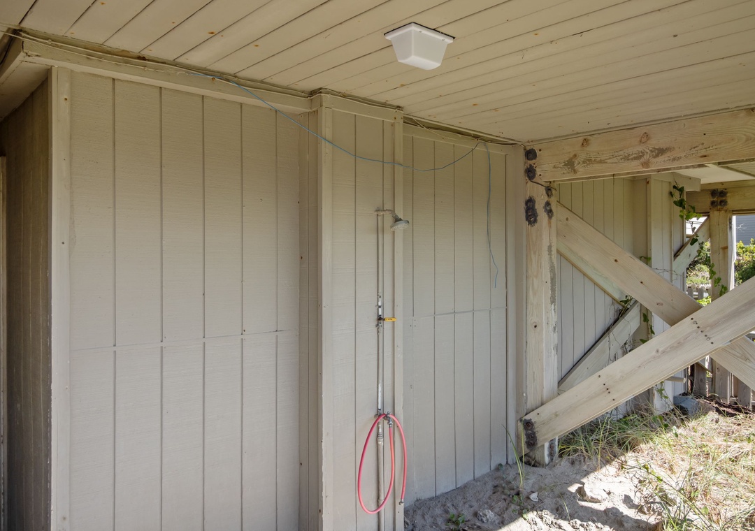 This rustic outdoor shower features natural wood walls and ceiling with a simple overhead fixture for refreshing rinses.