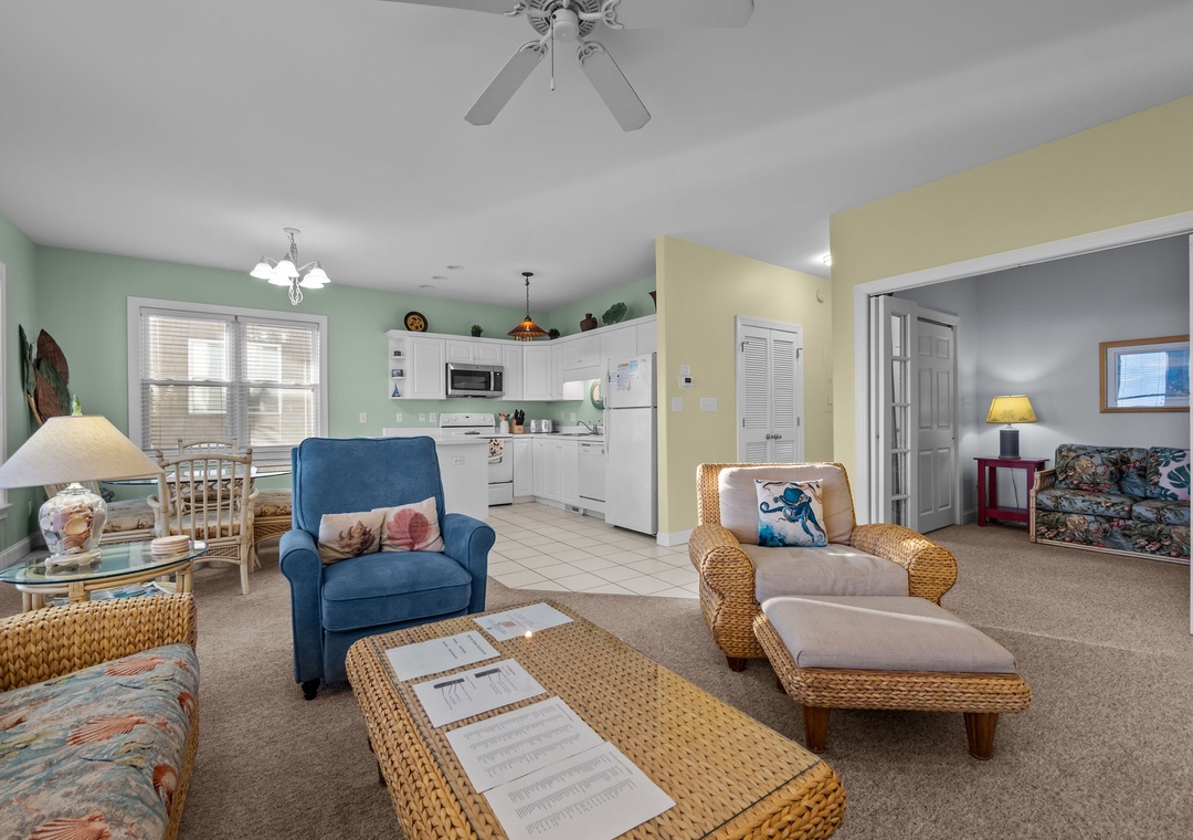 Relax in your spacious open-plan living area with comfortable seating, ceiling fan, and fully equipped kitchen for easy meal prep.